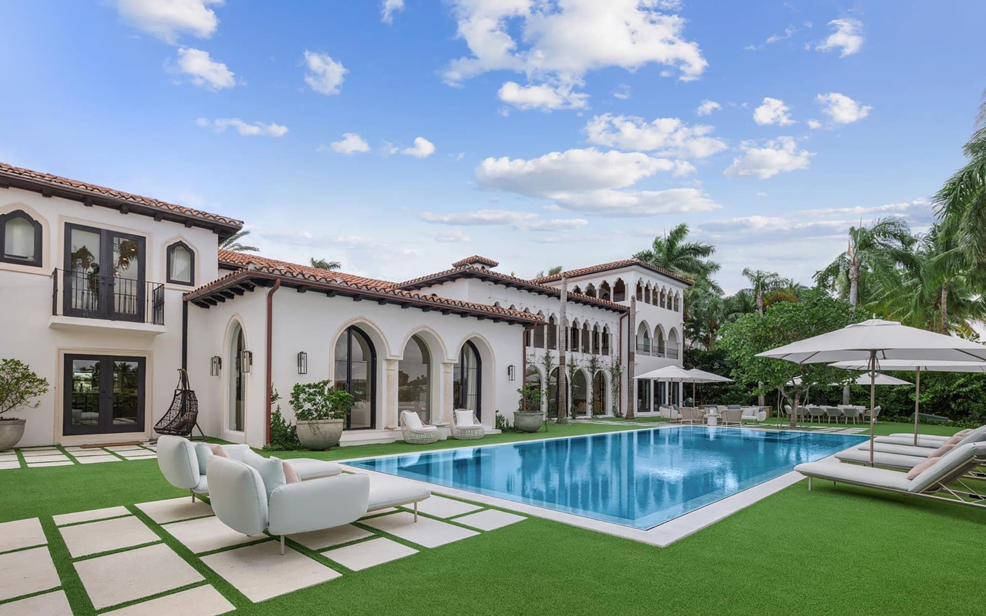 White stucco home with a swimming pool and palm trees