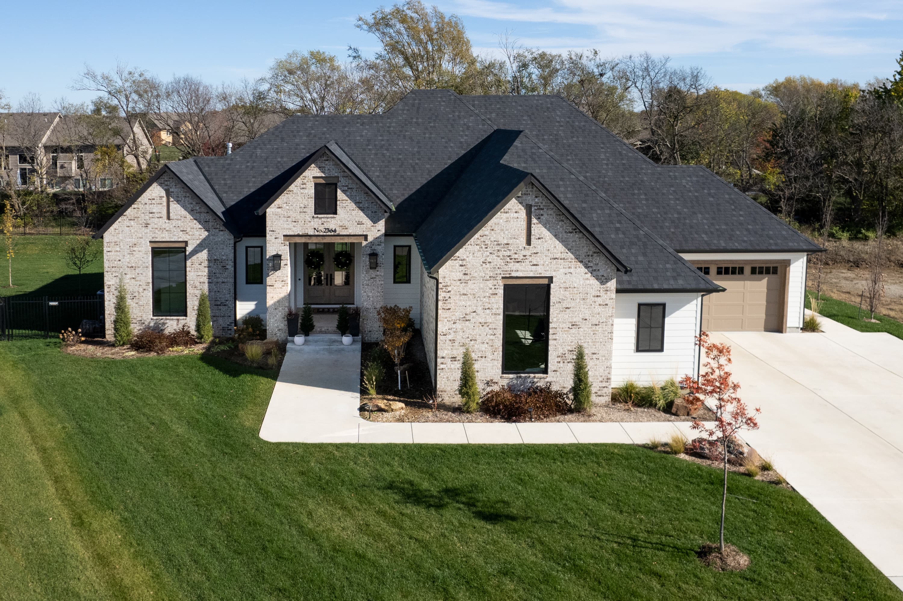 White brick home with a front lawn and dark roof